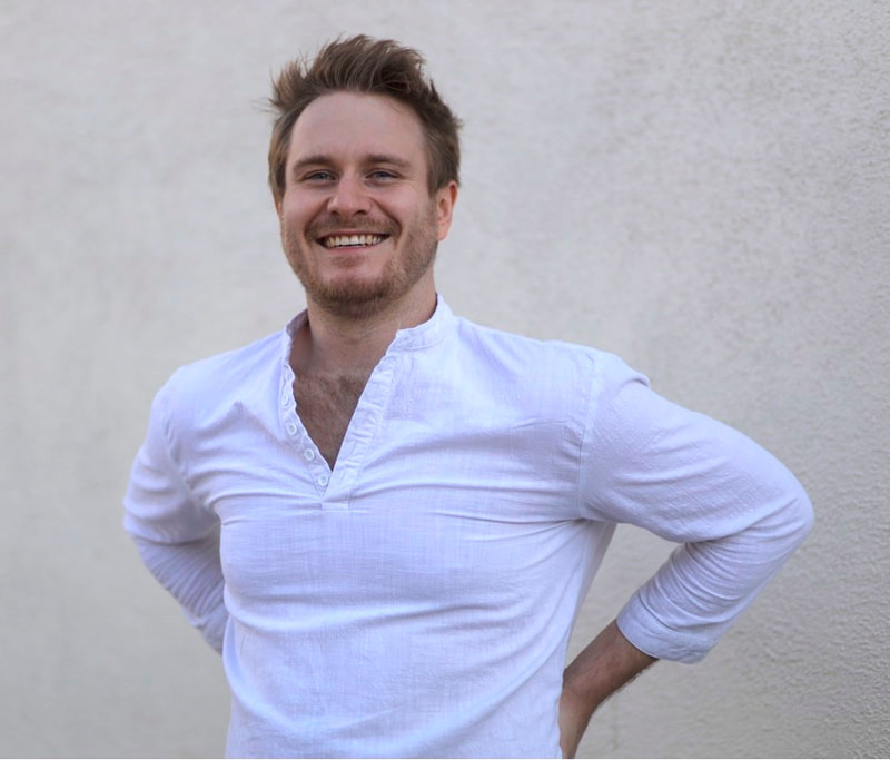 smiling man in white shirt posing in front of a wall