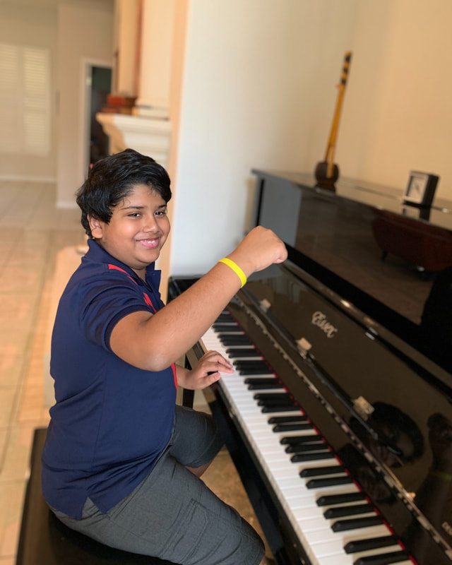 Student showing off yellow bracelet at the piano