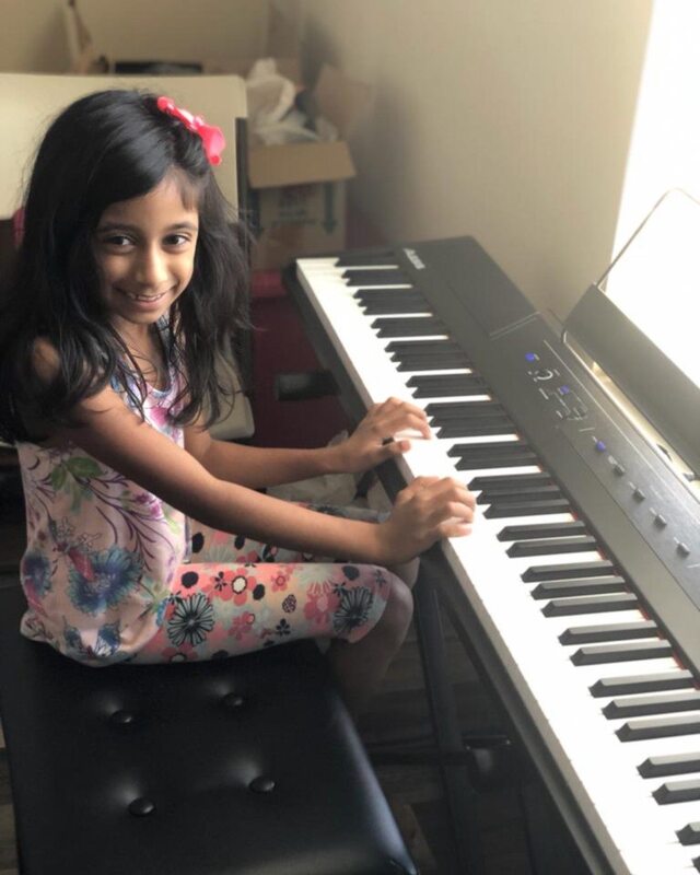 Student playing piano and smiling