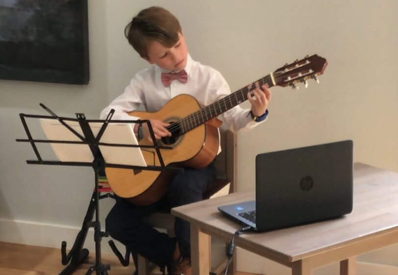 Student playing guitar in front of computer