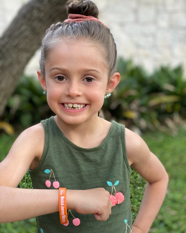 Student smiling and showing her orange bracelet