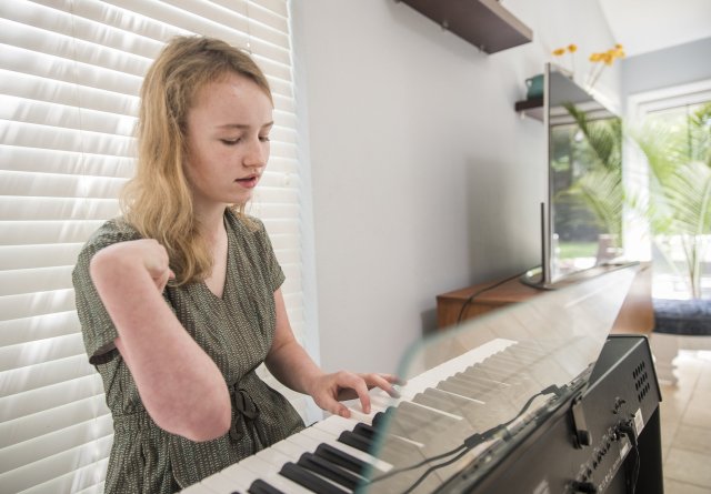 Student playing piano with one hand