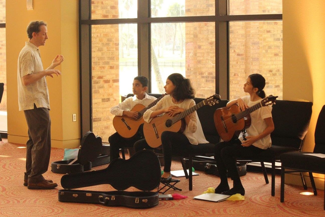 Teacher coaching a guitar trio
