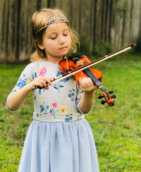 Child playing violin in a field