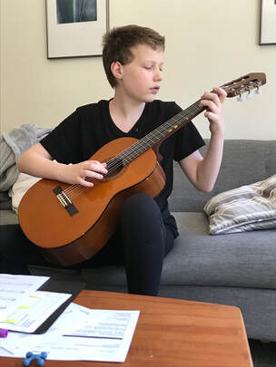 Student sitting on couch playing guitar