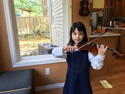 Student posing with violin in front of window