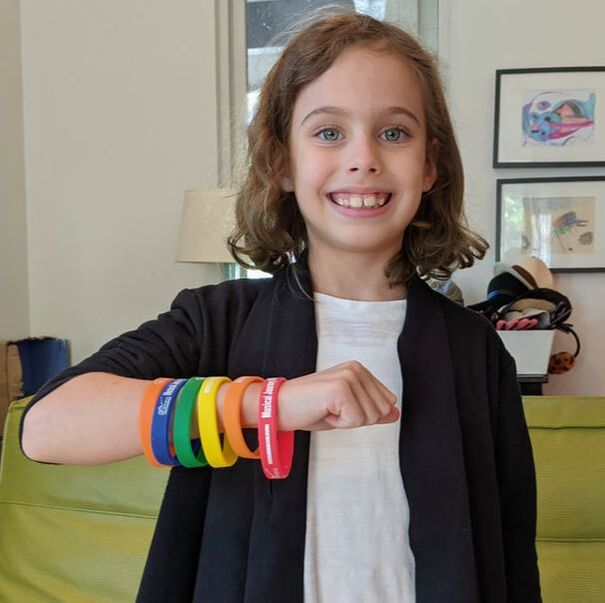 smiling student with six colored wristbands on arm