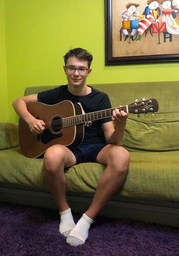 Student holding guitar on couch