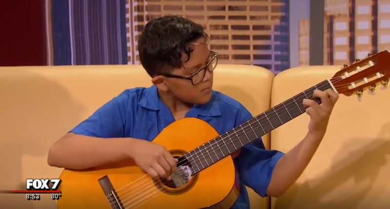 Student performing guitar on news station