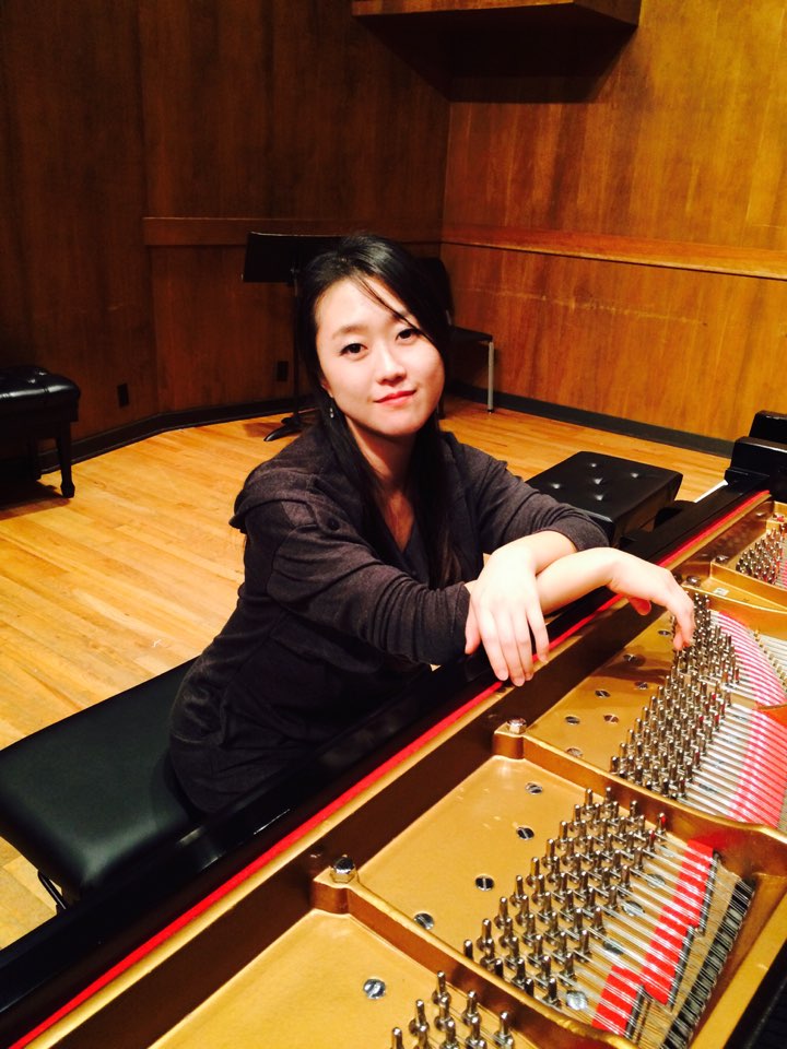 Yujung sitting with arms folded at piano