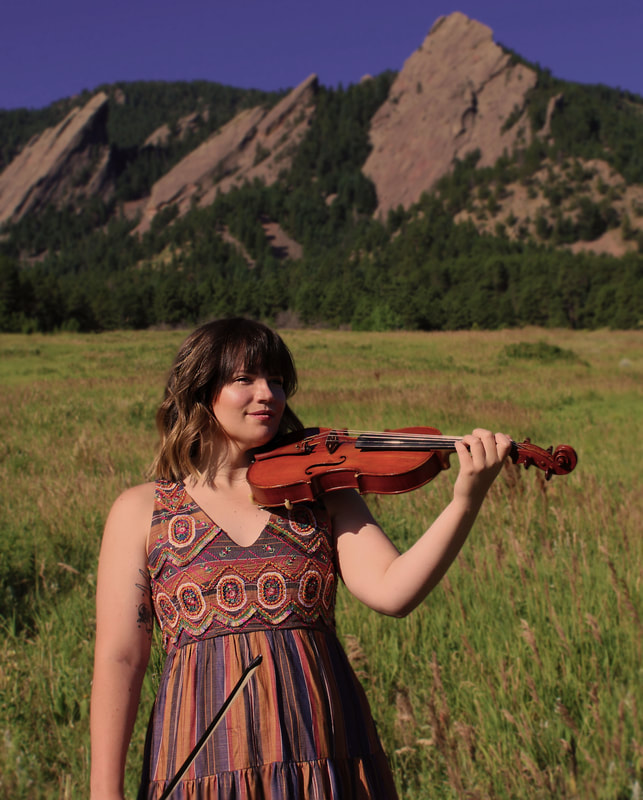 Mackenzie Hoffman holding violin in front of mountains