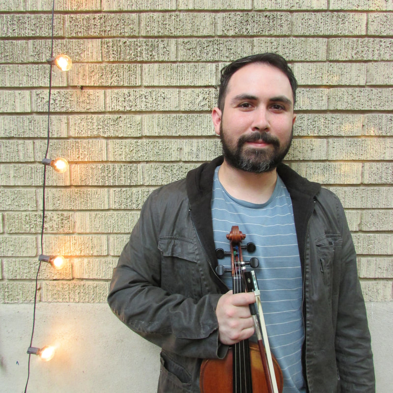 Ernesto Garza standing against wall with violin