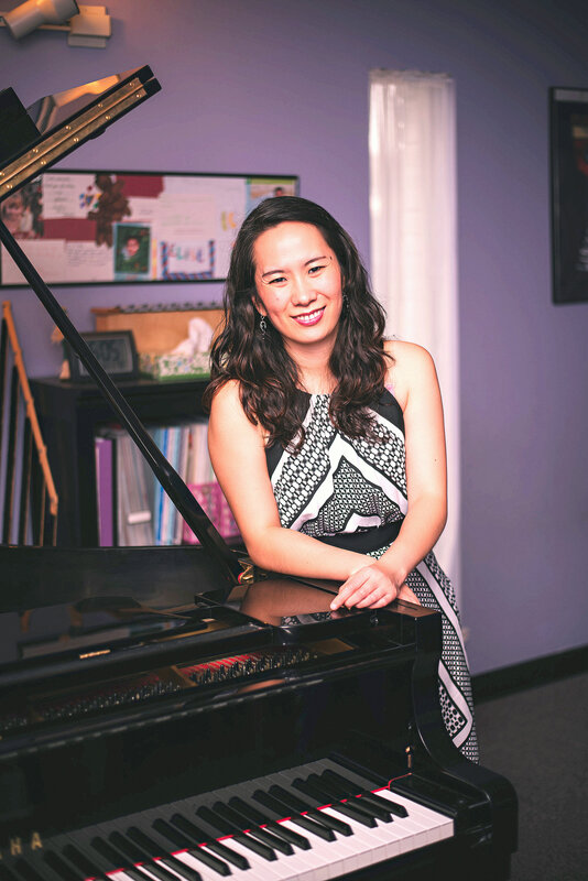 Joyce Wu standing and smiling at piano