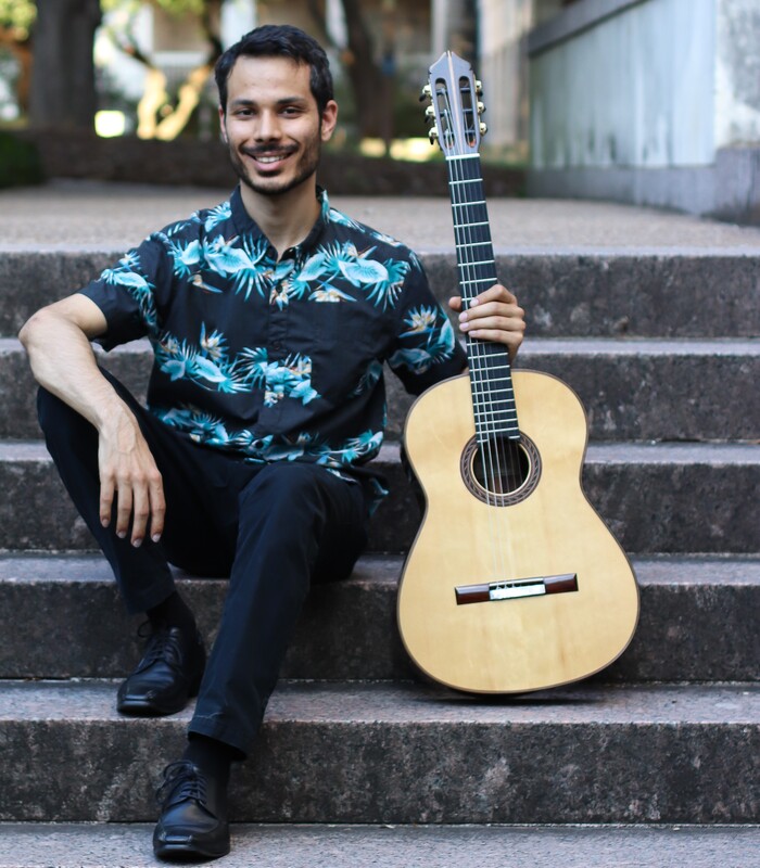 Vijay Meunier sitting on steps with guitar