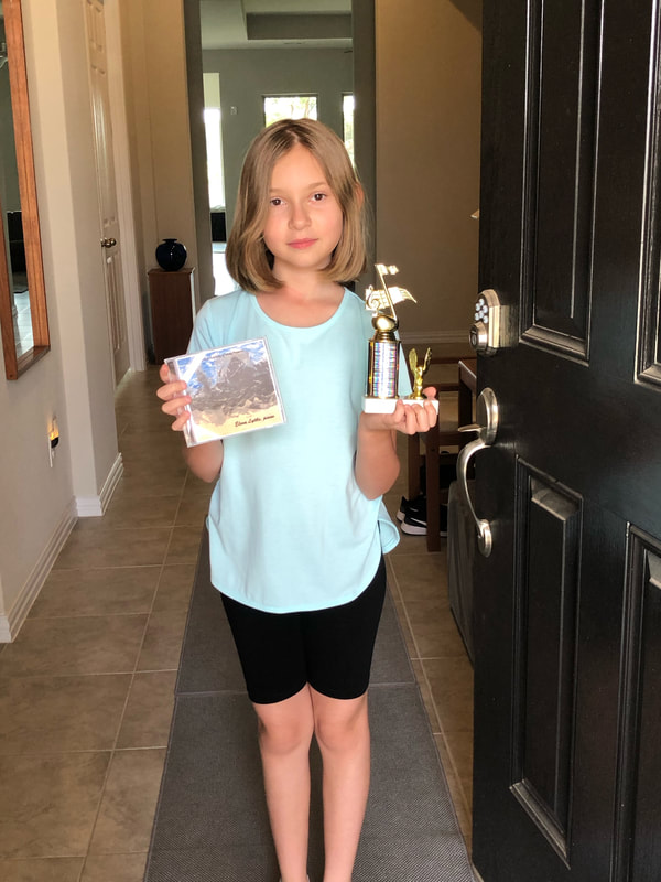young girl standing in doorway holding a music trophy and CD