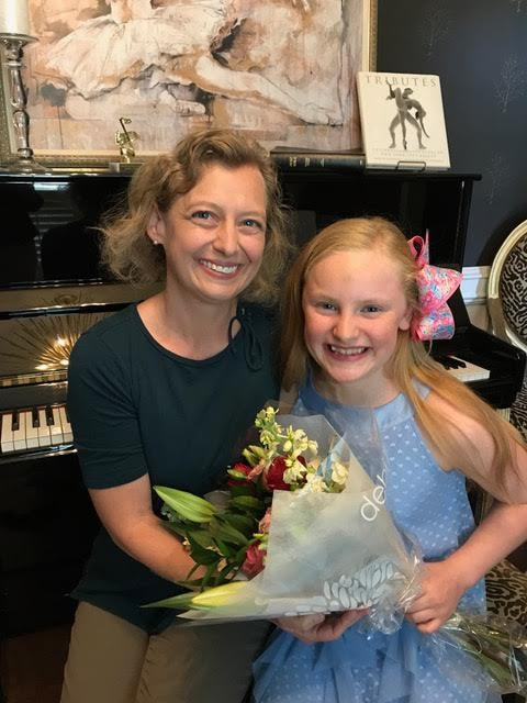 teacher and student sitting at piano and posing with flowers