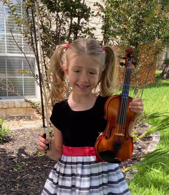 Student holding her violin and smiling outside