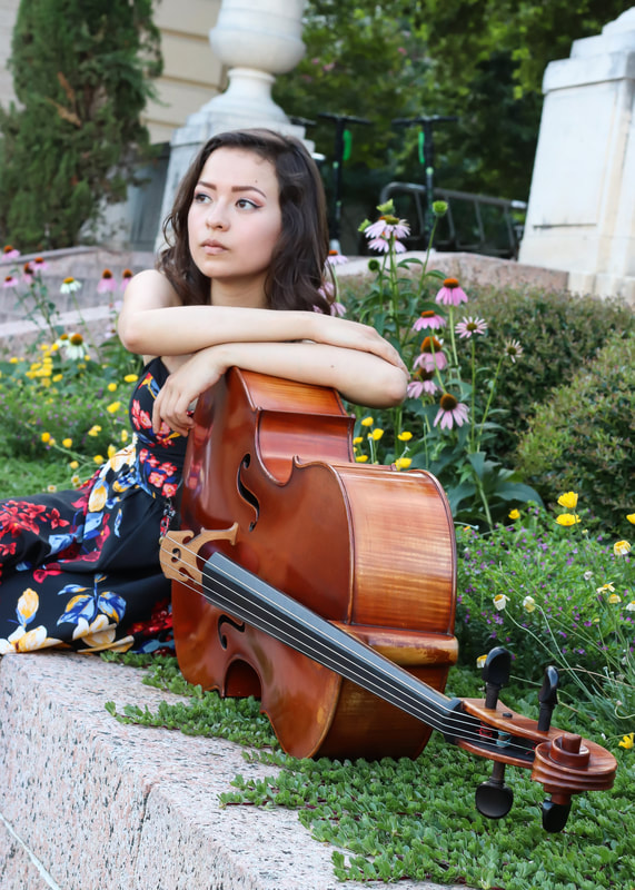 cello player sitting on ground with her cello in garden