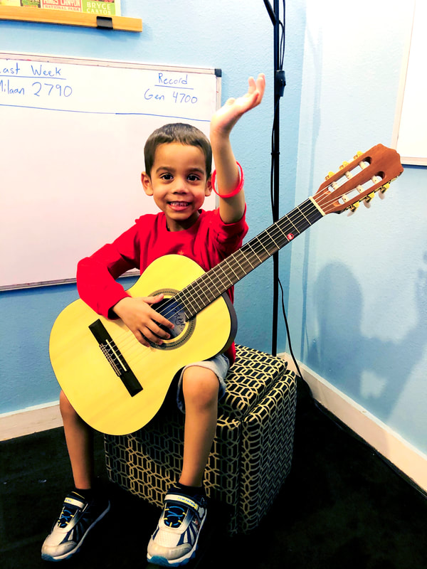 Student showing off his red bracelet with guitar