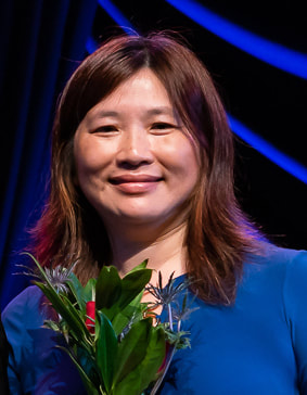 Wendy Kuo, Orpheus Director, smiling with flowers